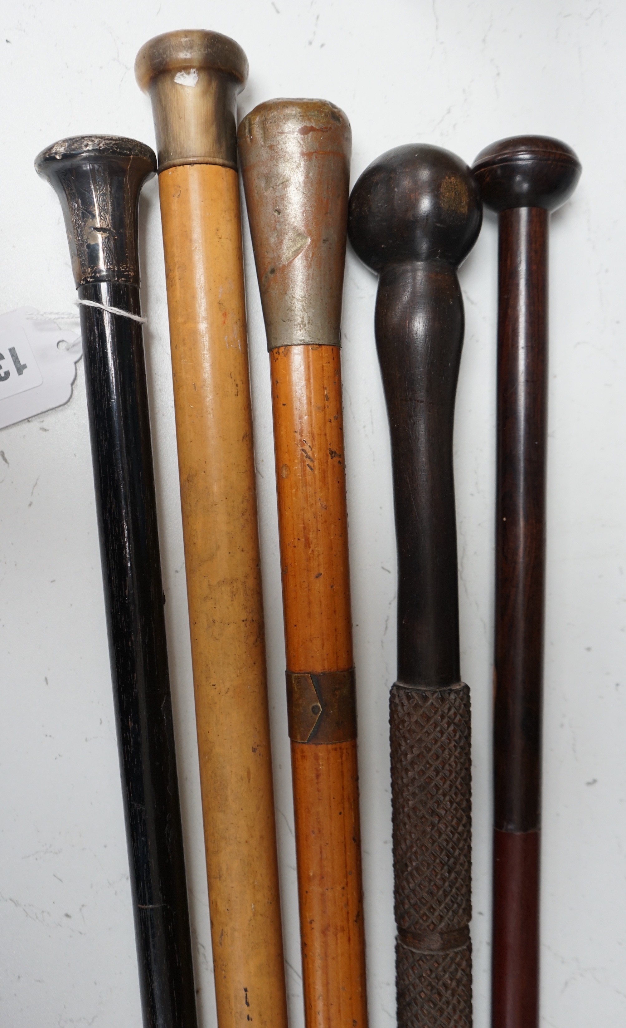 A collection of five walking sticks including one silver mounted and a Gladstone bag